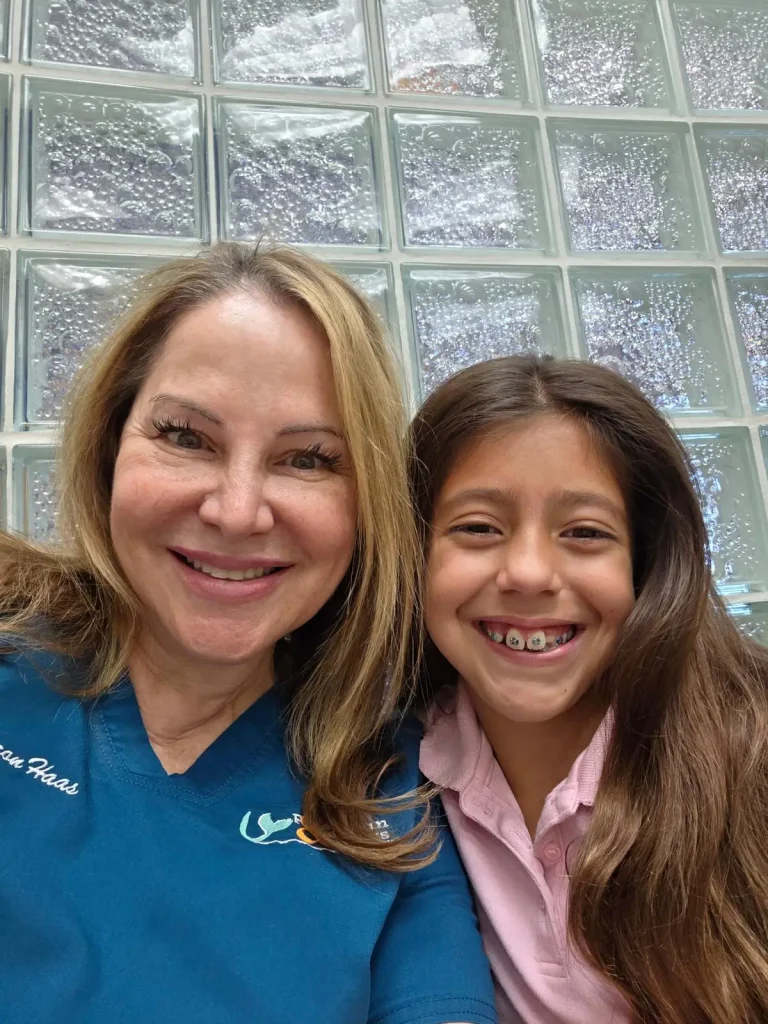 Sharon Haas next to kid patient with metal braces, both smiling