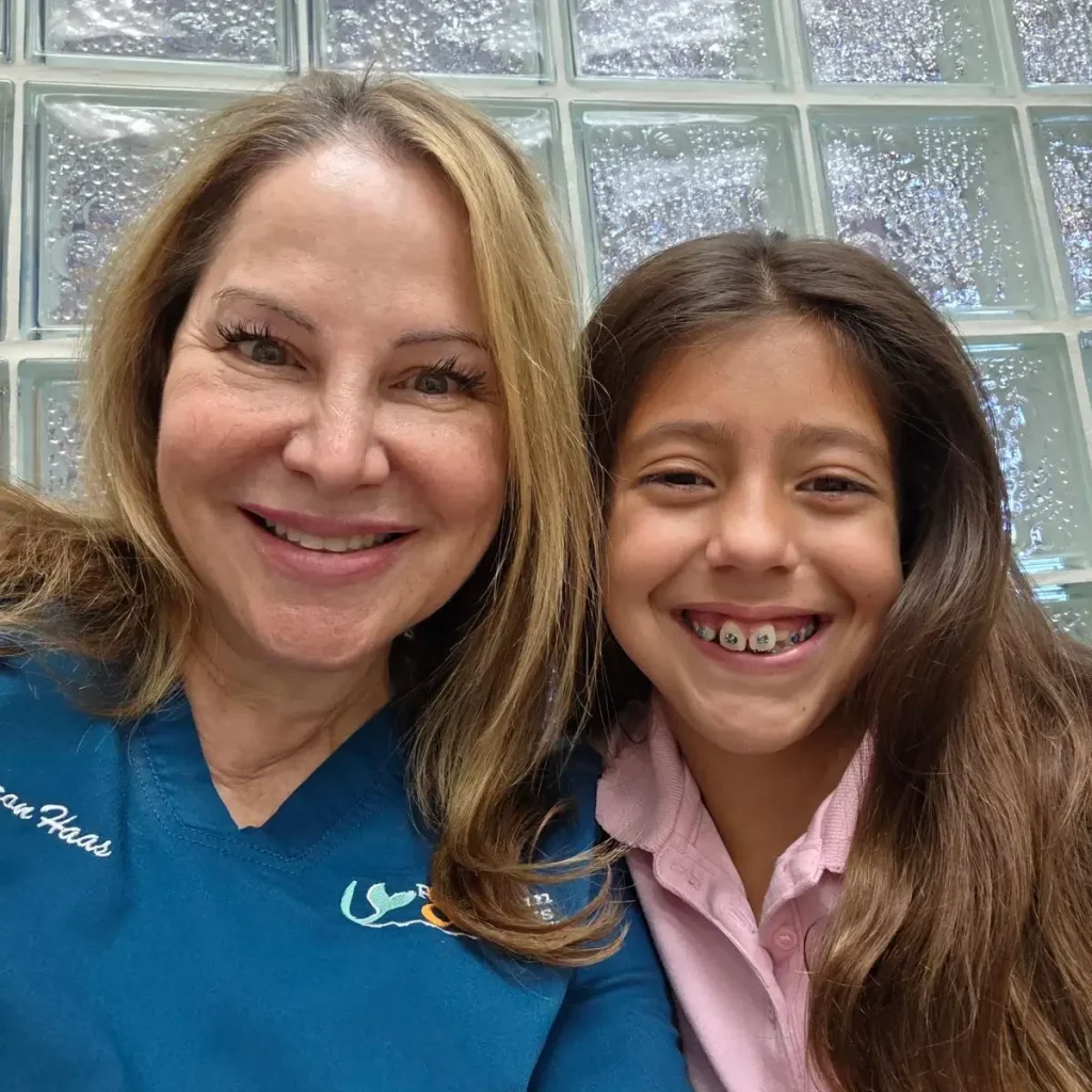 Sharon Haas next to kid patient with metal braces, both smiling